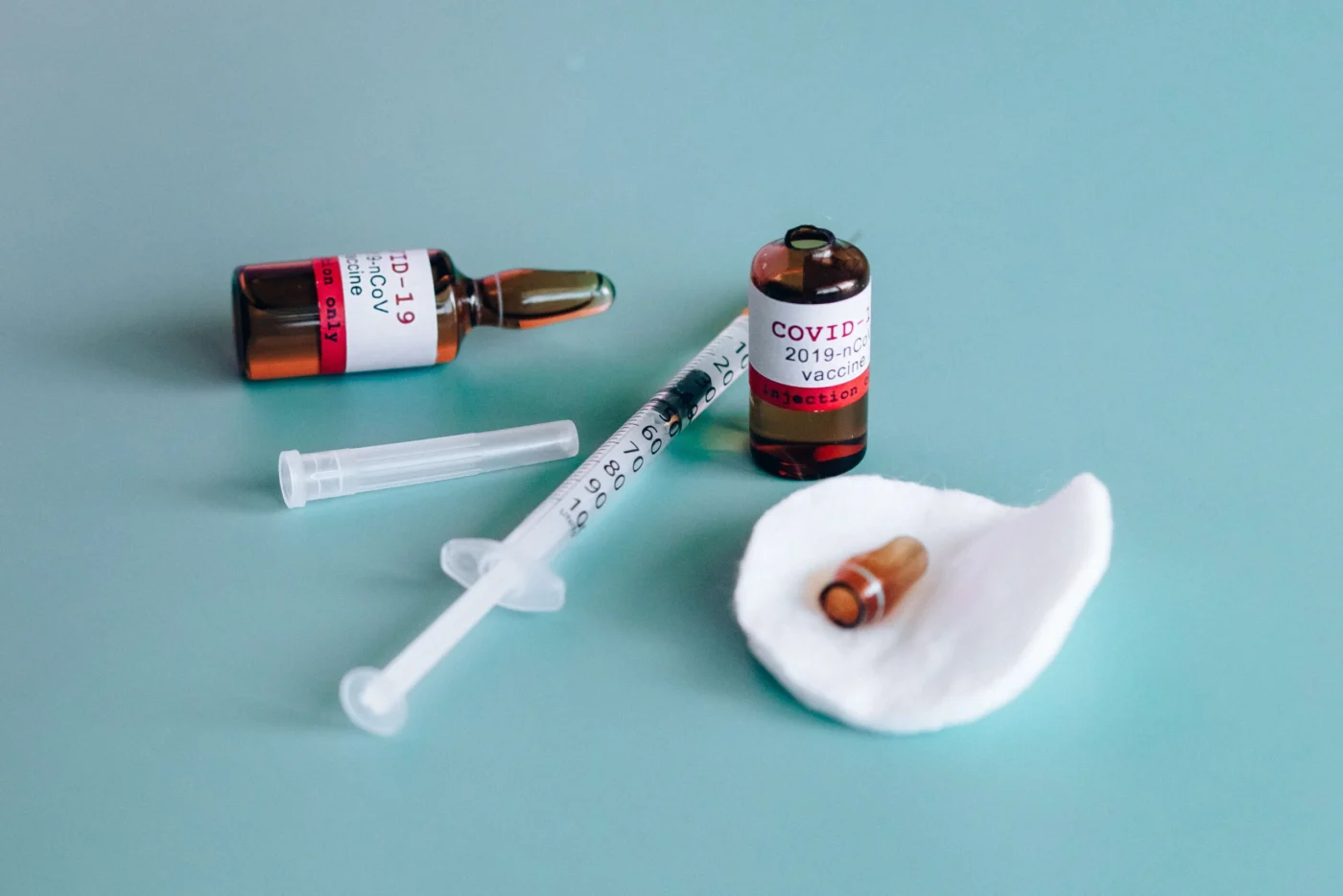 Vaccine vials and a syringe laid out on a clinic surface