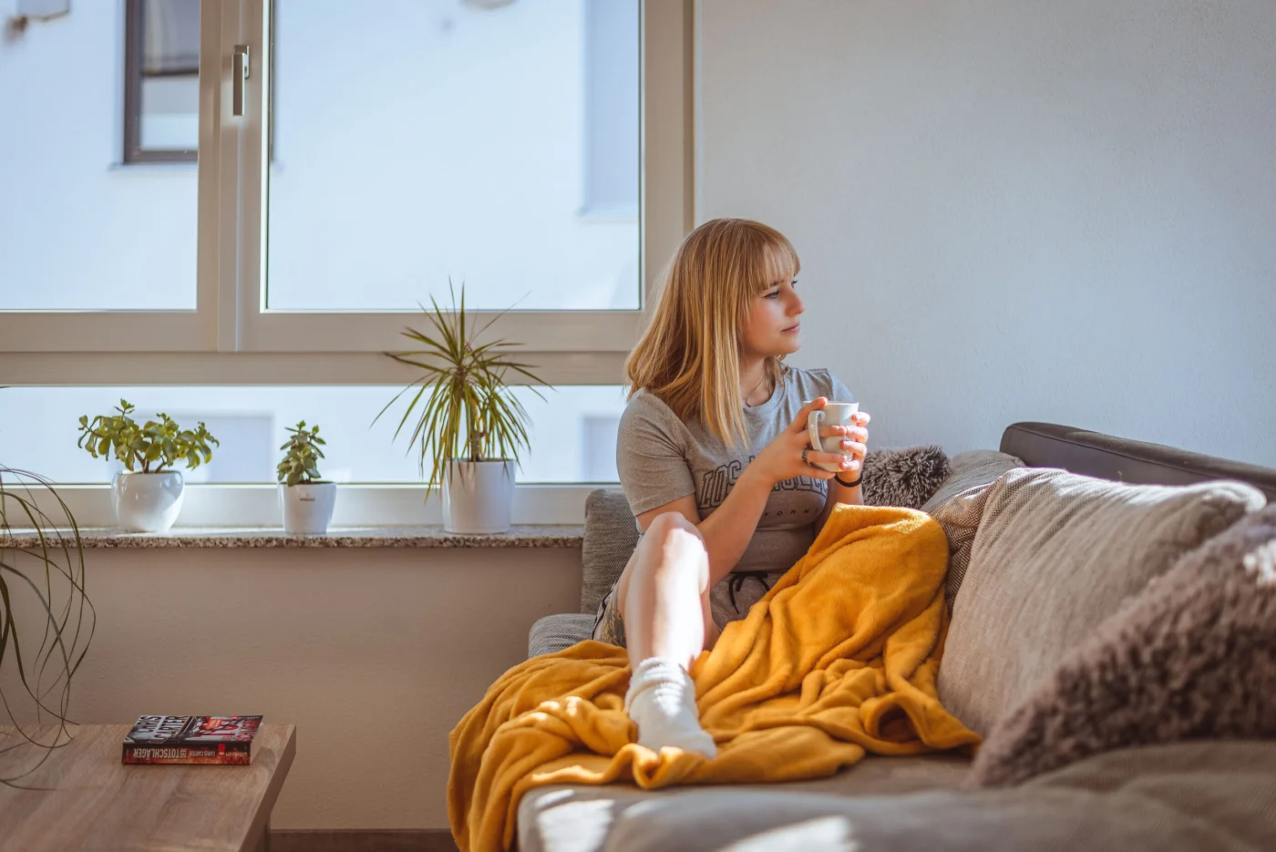 Woman relaxing on a sofa holding a warm drink for hydration and comfort