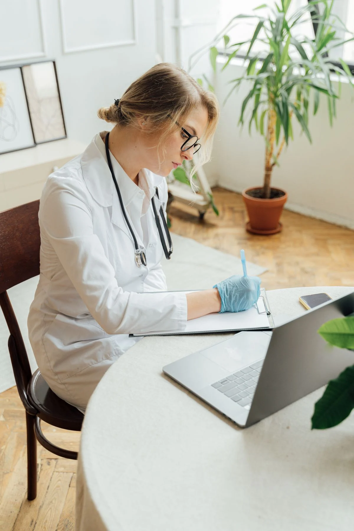 GP writing notes on a clipboard while preparing a medical certificate