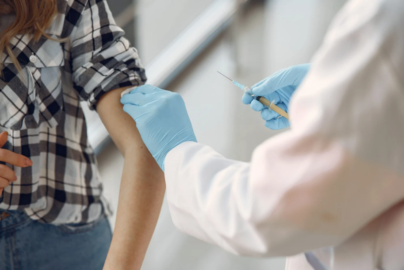 Doctor administering a vaccine injection into a patient's upper arm at a clinic