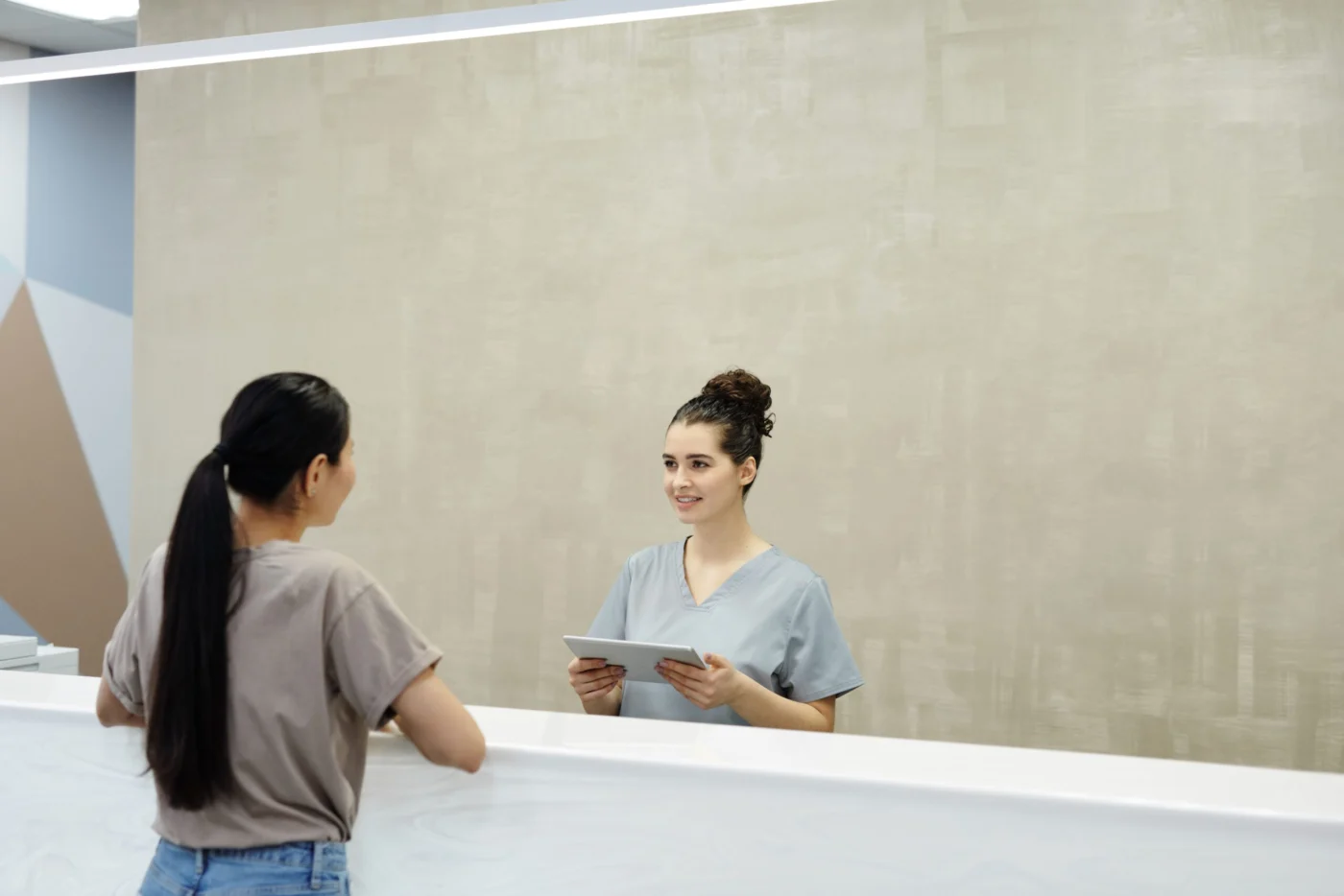 Smiling medical receptionist assisting a patient at the clinic front desk