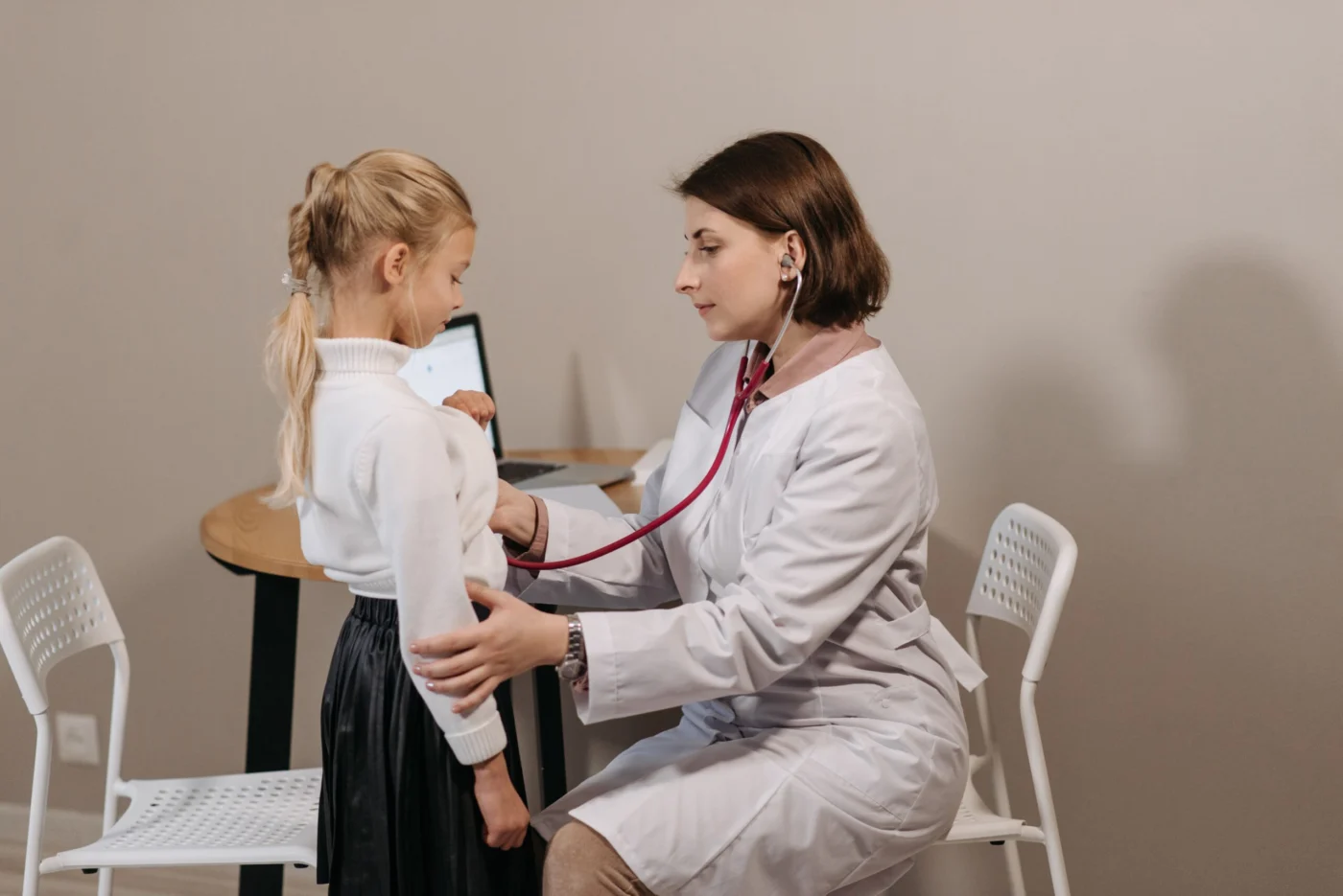 Female doctor listening to a young girl's chest with a stethoscope during a paediatric check-up