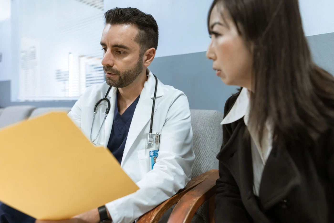Male doctor discussing vaccination and health records with an adult patient during a clinical consultation