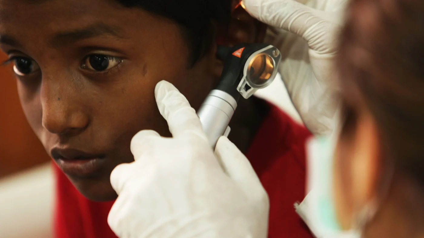 Doctor using an otoscope to examine a young boy's ear during a medical check-up