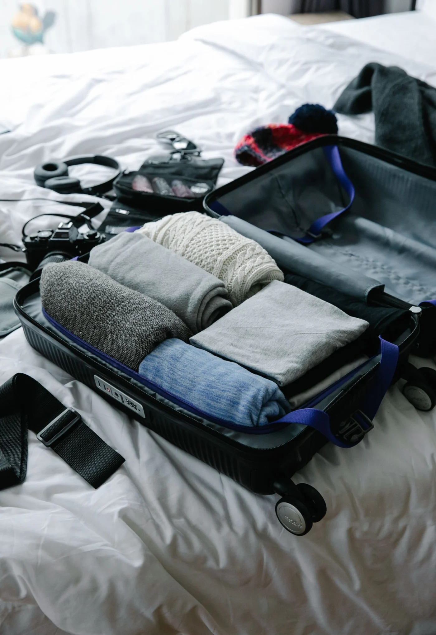 Open suitcase with neatly folded clothes being packed on a bed for an overseas trip